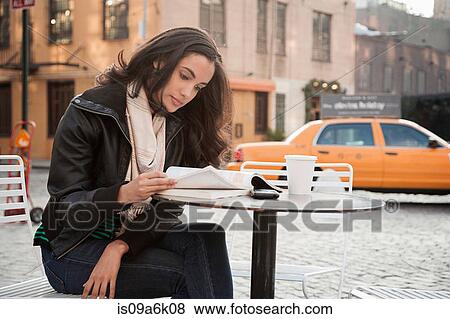 Stock Photo - Woman reading at sidewalk cafe. Fotosearch