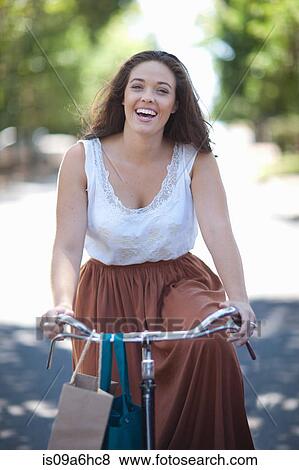 Woman riding bicycle in park View Large Photo Image Stock Photo - Woman riding bicycle in park. Fotosearch