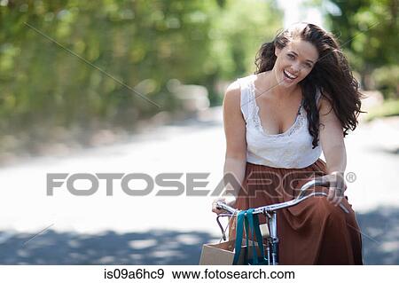 Woman riding bicycle in park View Large Photo Image Stock Photo - Woman riding bicycle in park. Fotosearch