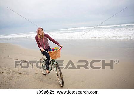 Stock Photography - Woman riding bicycle on beach. Fotosearch