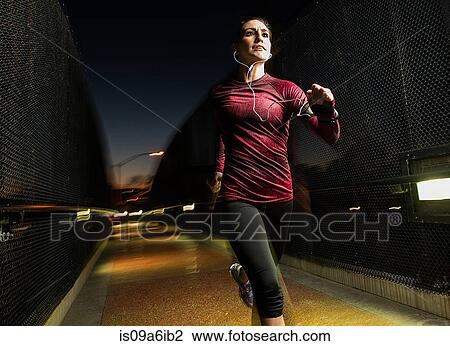 Stock Image - Woman running on pedestrian bridge. Fotosearch