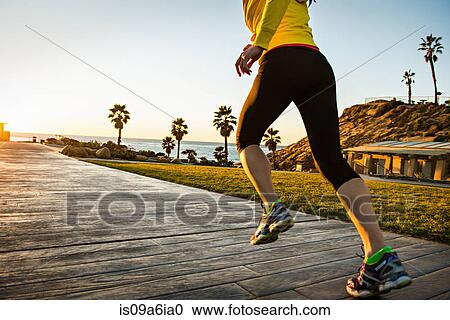 Stock Image - Woman running on wooden path. Fotosearch