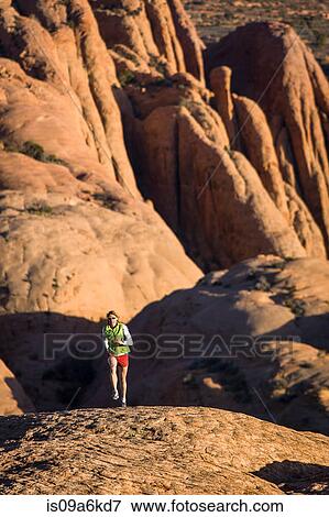 Stock Photo - Woman running over canyon hills. Fotosearch