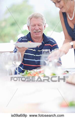Stock Photography - Woman serving food at table. Fotosearch