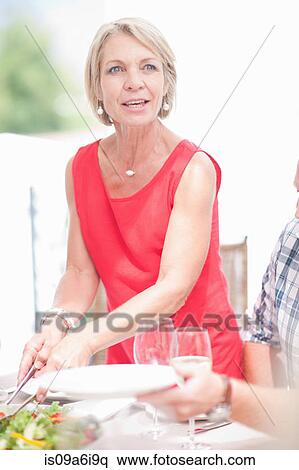 Stock Photography - Woman serving food at table. Fotosearch