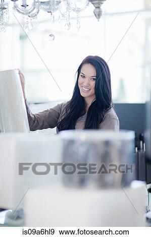 Stock Photo - Woman shopping for lamps in store. Fotosearch