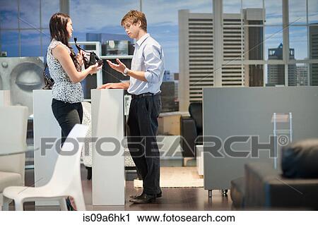 Stock Image - Woman shopping with salesman in store. Fotosearch