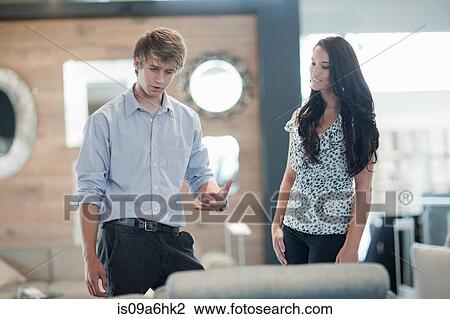 Stock Image - Woman shopping with salesman in store. Fotosearch