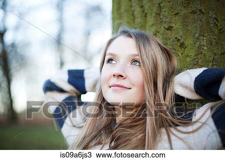 Woman sitting by tree outdoors View Large Photo Image Stock Image - Woman sitting by tree outdoors. Fotosearch