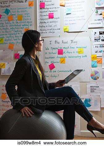 Picture - Woman sitting on exercise ball with digital tablet. Fotosearch