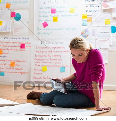 Stock Image - Woman sitting on floor with digital tablet. Fotosearch