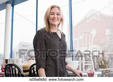 Stock Image - Woman smiling in thrift store. Fotosearch