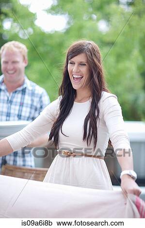 Stock Image - Woman spreading blanket outdoors. Fotosearch