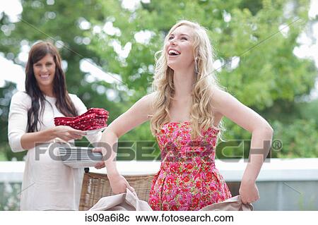 Stock Image - Woman spreading tablecloth outdoors. Fotosearch