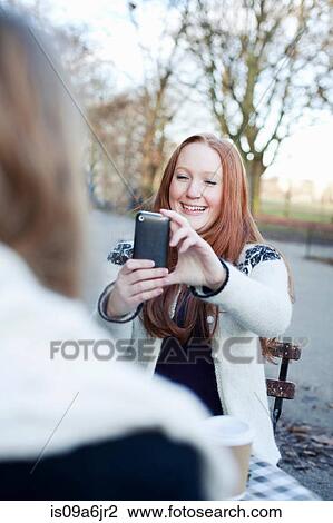 Stock Image - Woman taking cell phone picture. Fotosearch