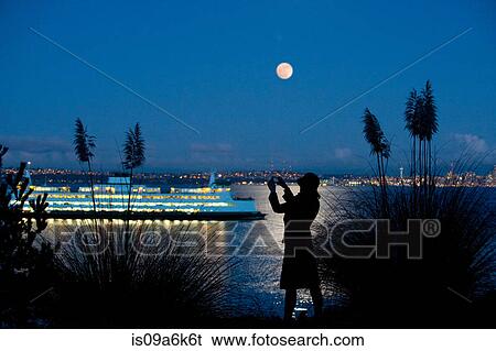 Stock Photograph - Woman taking picture of cruise ship. Fotosearch