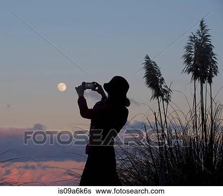 Stock Photograph - Woman taking picture of moon. Fotosearch