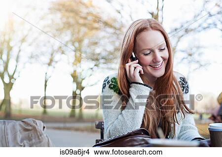 Picture - Woman talking on cell phone outdoors. Fotosearch