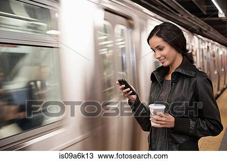 Woman using cell phone at subway station View Large Photo Image Stock Image - Woman using cell phone at subway station. Fotosearch