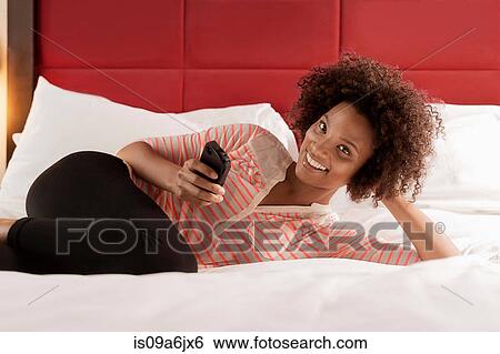 Woman using cell phone on bed View Large Photo Image Stock Photograph - Woman using cell phone on bed. Fotosearch