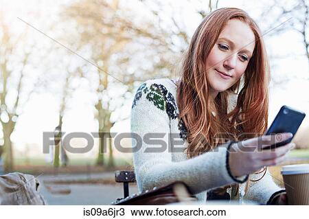 Stock Image - Woman using cell phone outdoors. Fotosearch