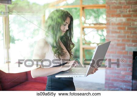 Stock Photo - Woman using laptop in living room. Fotosearch