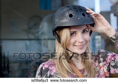 Stock Image - Woman wearing bicycle helmet outdoors. Fotosearch