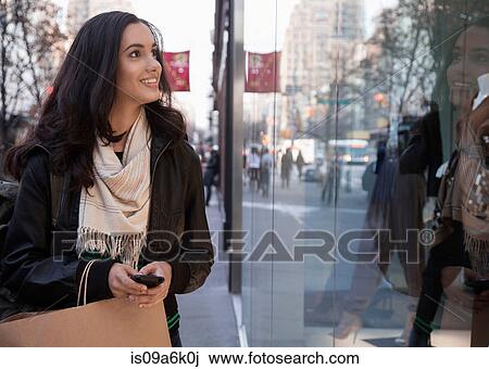 Stock Image - Woman window shopping on city street. Fotosearch