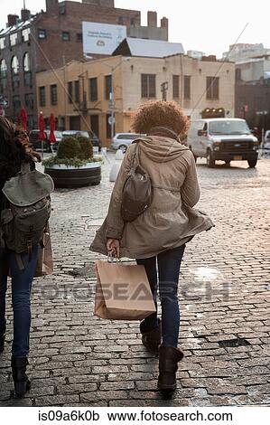 Stock Image - Woman with shopping bag on city street. Fotosearch