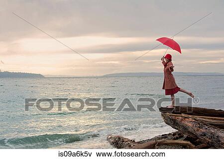 Woman with umbrella on coastal cliff View Large Photo Image Stock Photo - Woman with umbrella on coastal cliff. Fotosearch