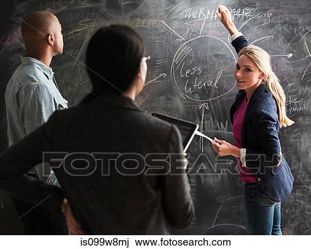 Woman writing on blackboard, colleagues watching View Large Photo Image Stock Image - Woman writing on blackboard, colleagues watching. Fotosearch