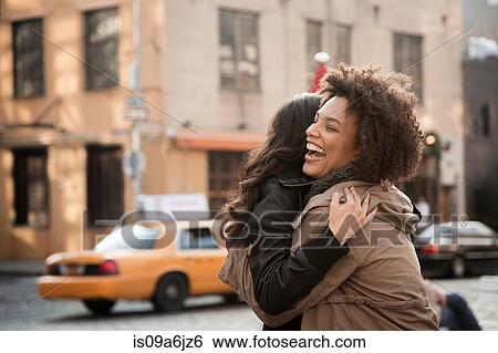 Stock Photograph - Women hugging on city street. Fotosearch