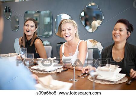 Stock Photo - Women laughing at dinner table. Fotosearch
