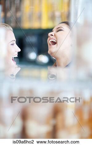 Stock Image - Women laughing together in store. Fotosearch