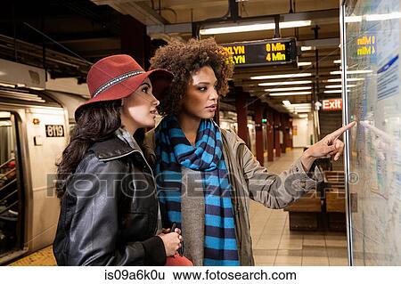 Stock Photograph - Women reading map in subway station. Fotosearch