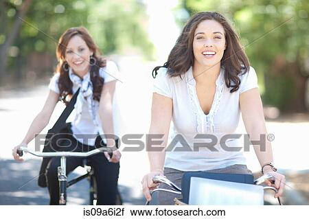 Stock Image - Women riding bicycles in park. Fotosearch