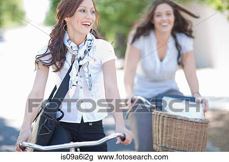 Stock Image - Women riding bicycles in park. Fotosearch