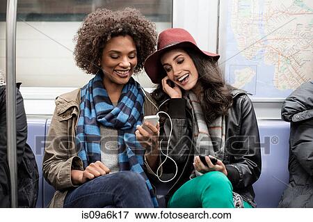 Women sharing earphones on subway View Large Photo Image Stock Photo - Women sharing earphones on subway. Fotosearch