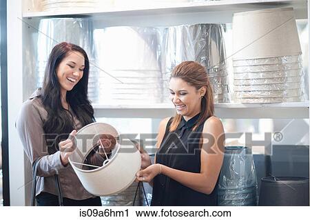 Stock Image - Women shopping for lamps in store. Fotosearch