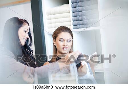 Stock Image - Women shopping for towels in store. Fotosearch