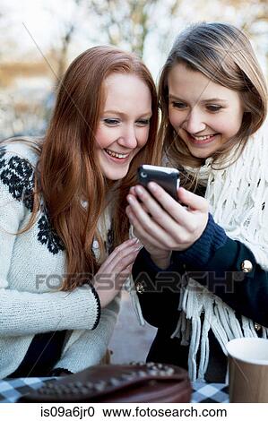 Stock Image - Women using cell phone together. Fotosearch