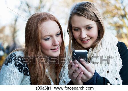 Stock Image - Women using cell phone together. Fotosearch