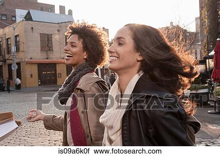 Stock Image - Women walking together on city street. Fotosearch