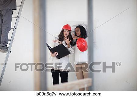 Architect and designer discussing plans on construction site View Large Photo Image Stock Photo - Architect and designer discussing plans on construction site. Fotosearch