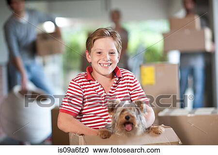 Stock Image - Boy moving house with dog in box. Fotosearch
