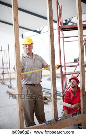 Builder and project manager measuring construction frame View Large Photo Image Stock Photo - Builder and project manager measuring construction frame. Fotosearch