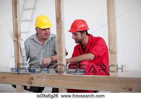Stock Photograph - Builder and project manager pointing at spirit level. Fotosearch