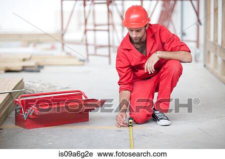 Stock Image - Builder with tool box and pencil measuring floor on construction site. Fotosearch