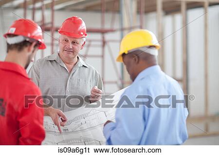 Builders holding and looking at a blueprint View Large Photo Image Stock Photograph - Builders holding and looking at a blueprint. Fotosearch