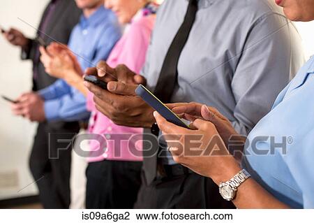 Stock Image - Business colleagues using cell phones. Fotosearch